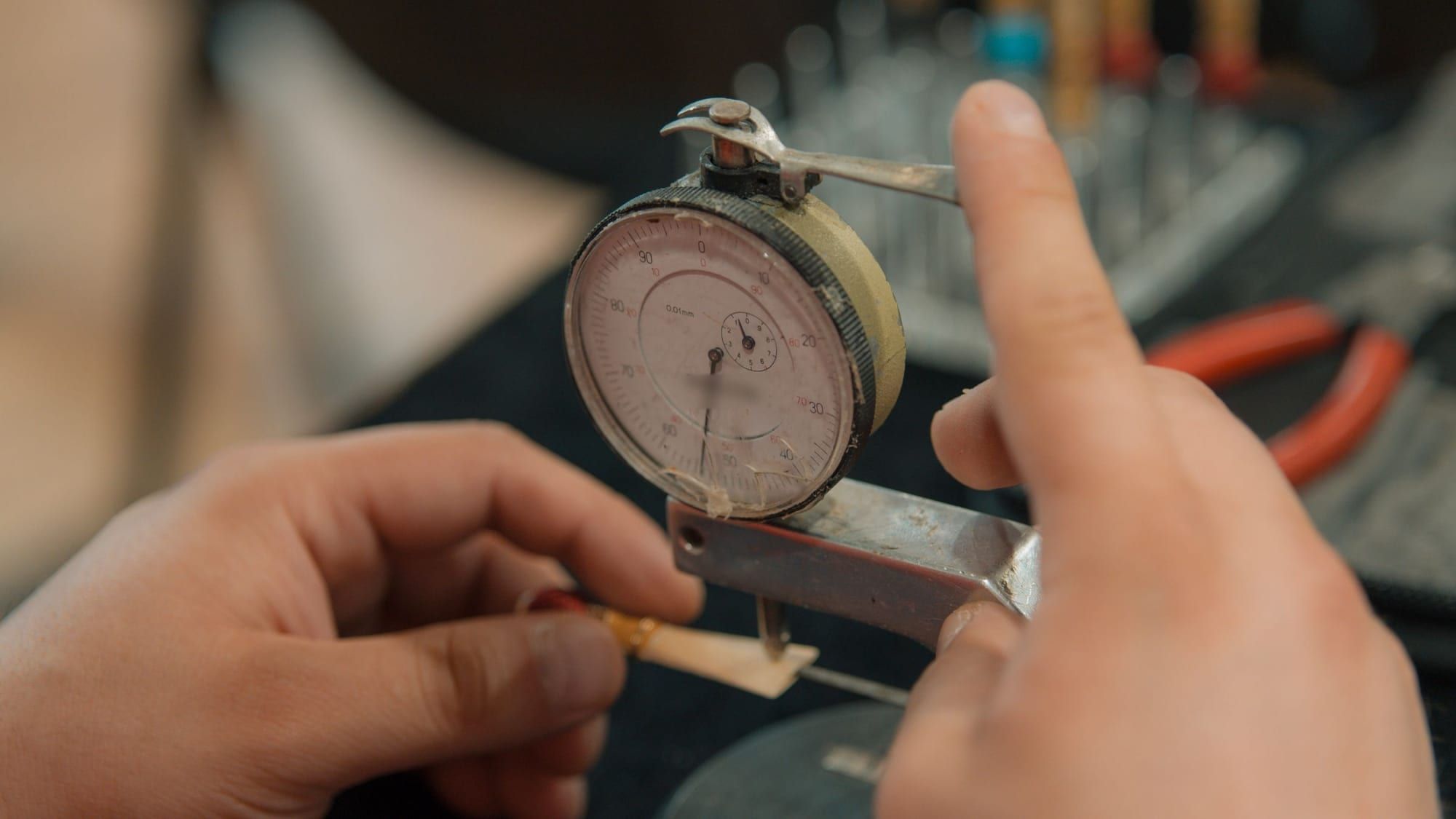 Hands checking a dial gauge on a test fixture