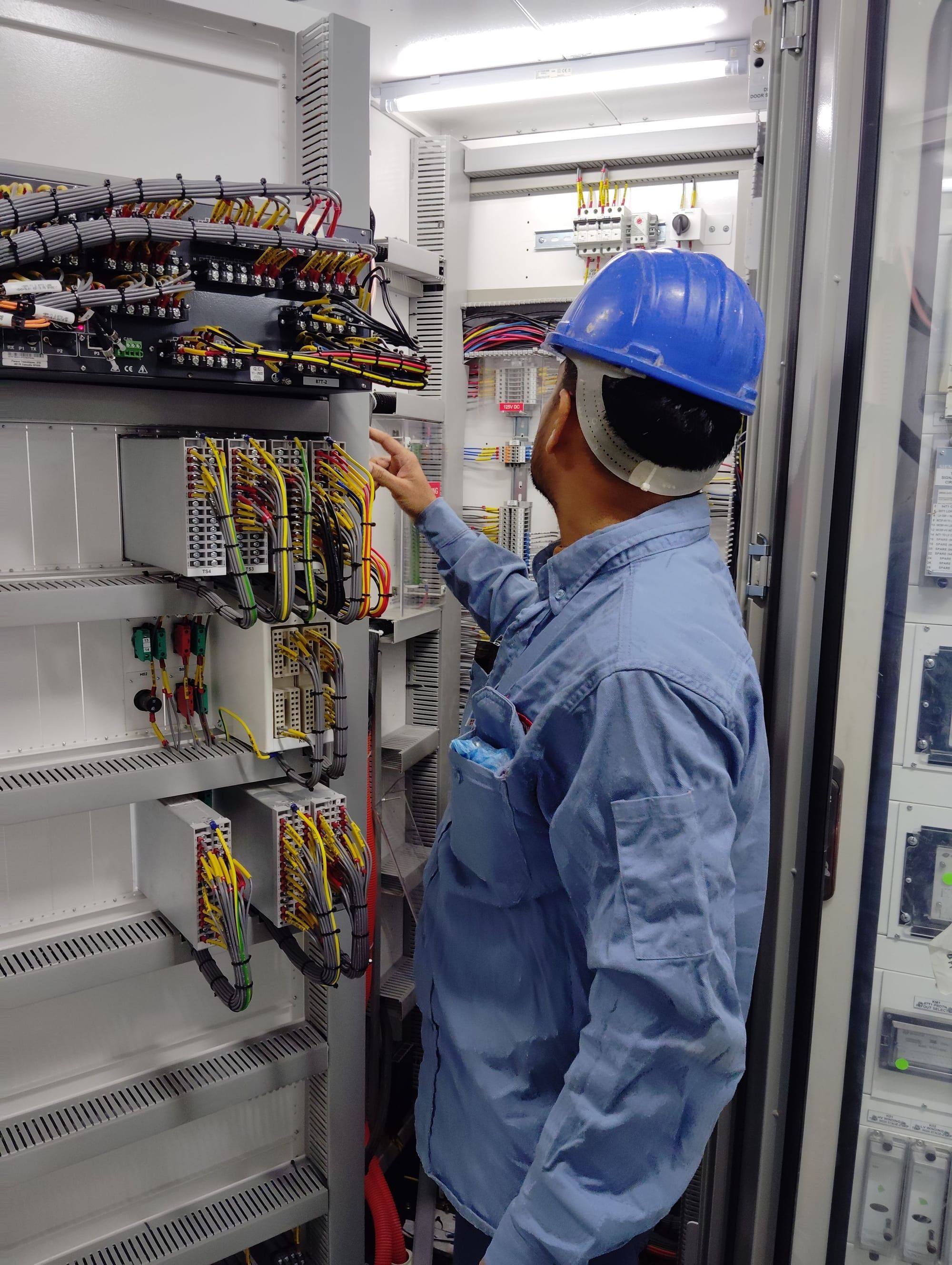 A technician checking wiring inside an electrical panel