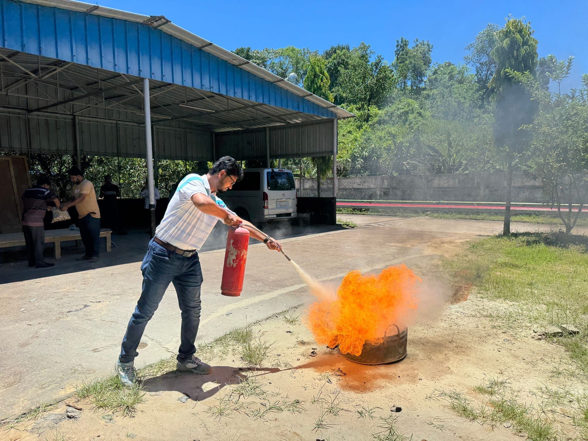 A man putting out a practice fire with an extinguisher