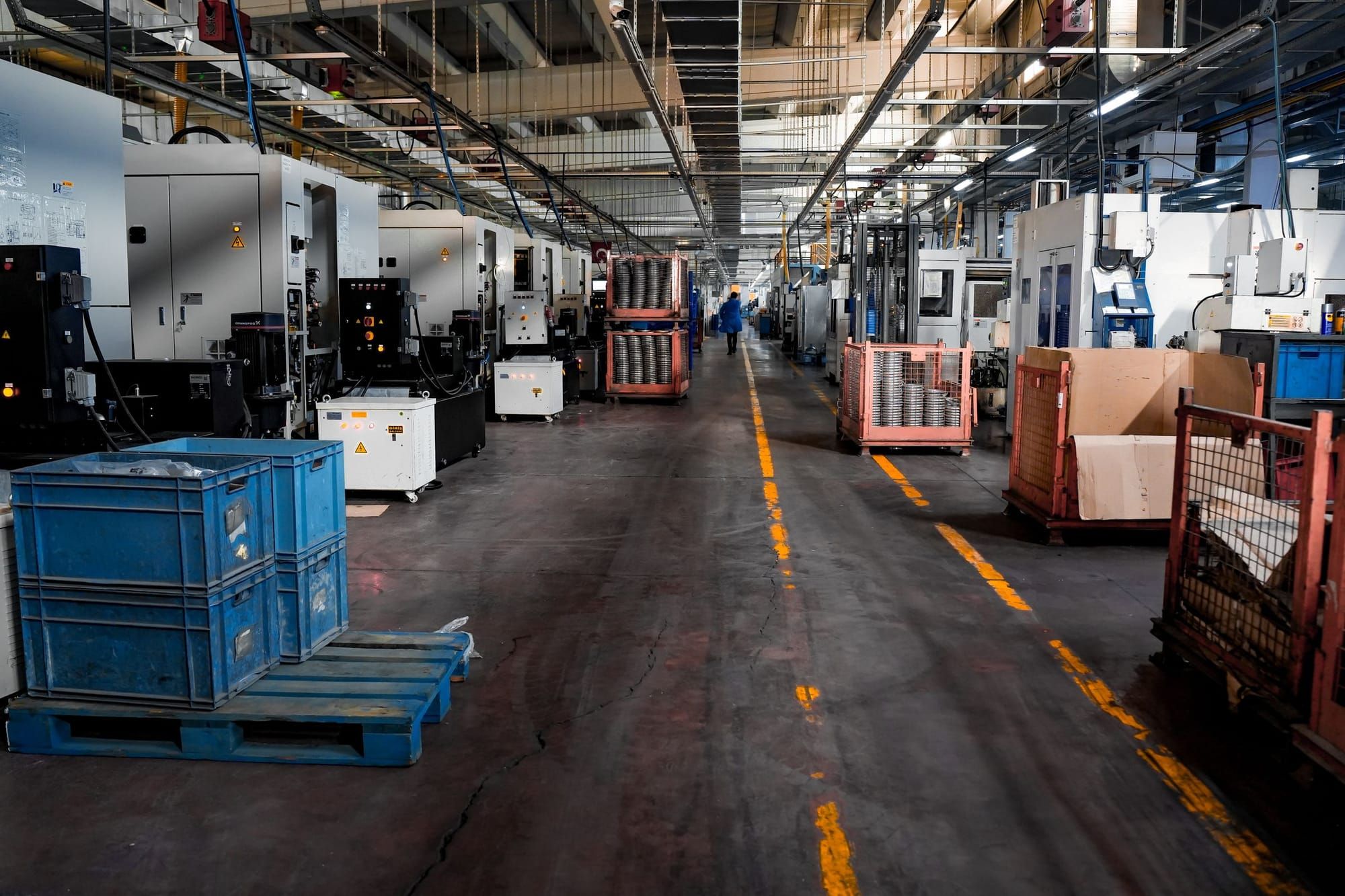 A machine-shop aisle lined with CNC machines and parts crates